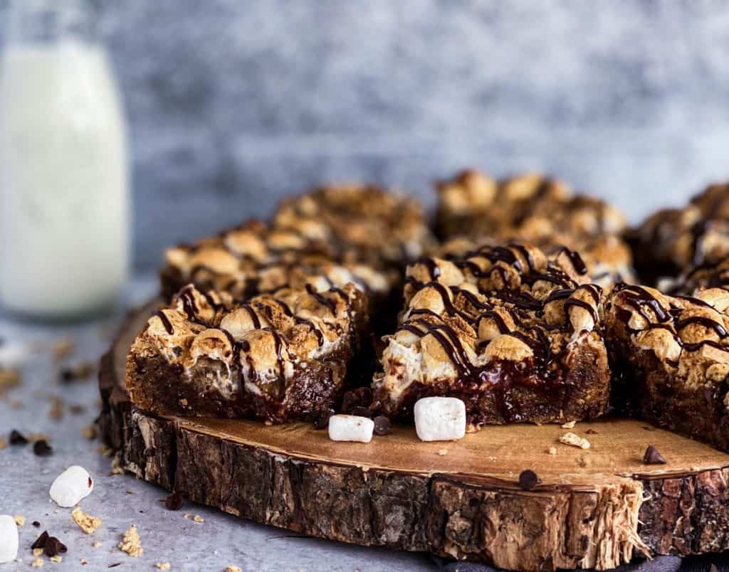 Easy s'mores bars sitting on a wooden cake stand, they are chewy, gooey dessert full of chocolate