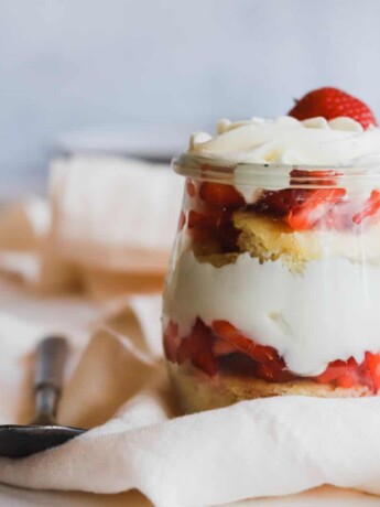 1 easy strawberry shortcake trifles in a jar on a flowing napkin.