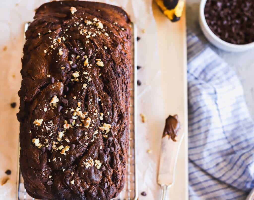 Nutella swirled banana bread with pecans and chocolate chips on top of the loaf.