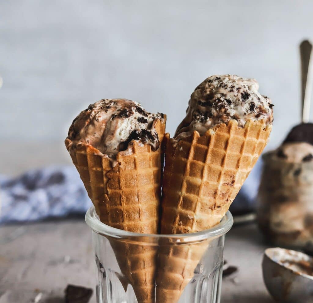 No-churn oreo and hot fudge ice cream make with sweetened condensed milk in 2 waffle cones.