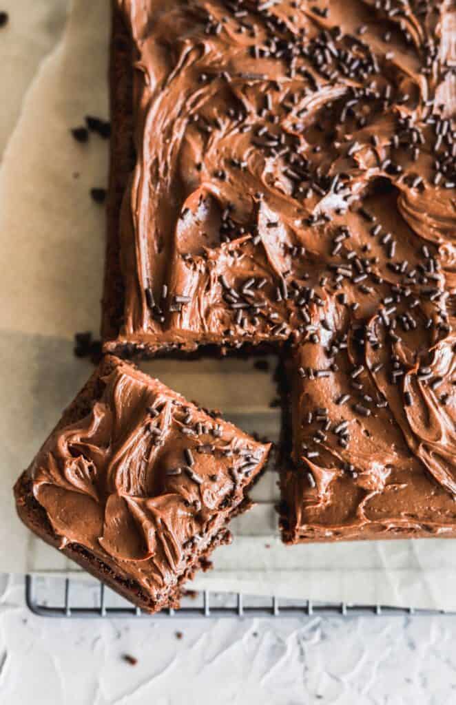 Chocolate chip sheet cake with 1 slice being taken out. It is topped with chocolate cream cheese buttercream.