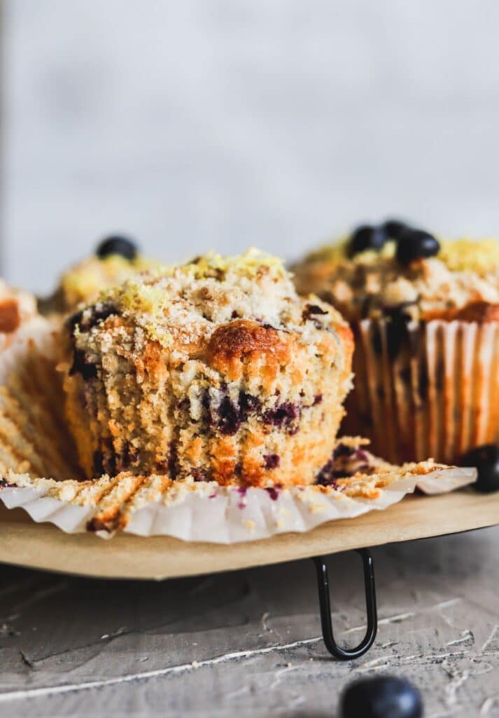 Lemon blueberry muffins with a lemon crumb topping with the muffin liners taken off.