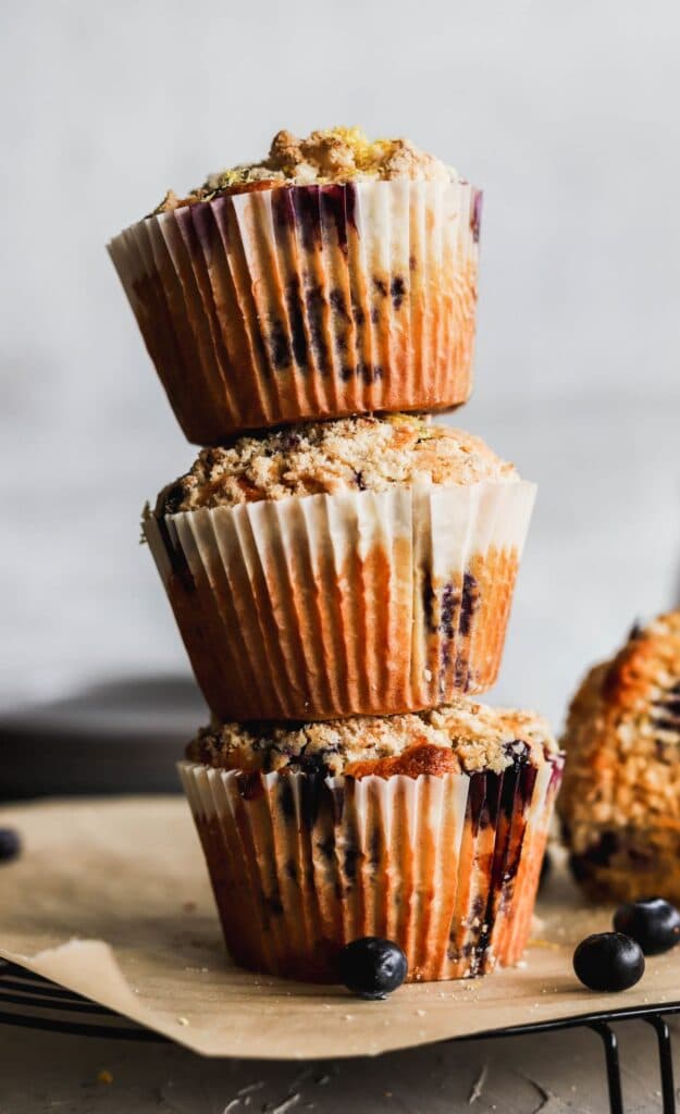 A stack of 3 jumbo lemon blueberry muffins stacked up high.