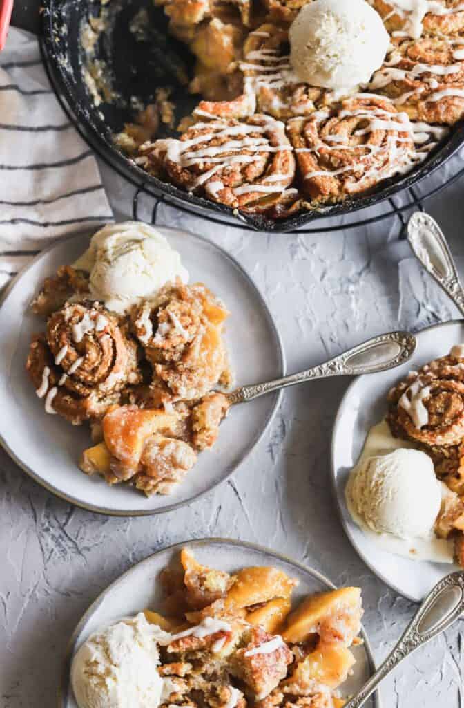 Peach cobbler with cinnamon oat swirl biscuits with ice cream on top.