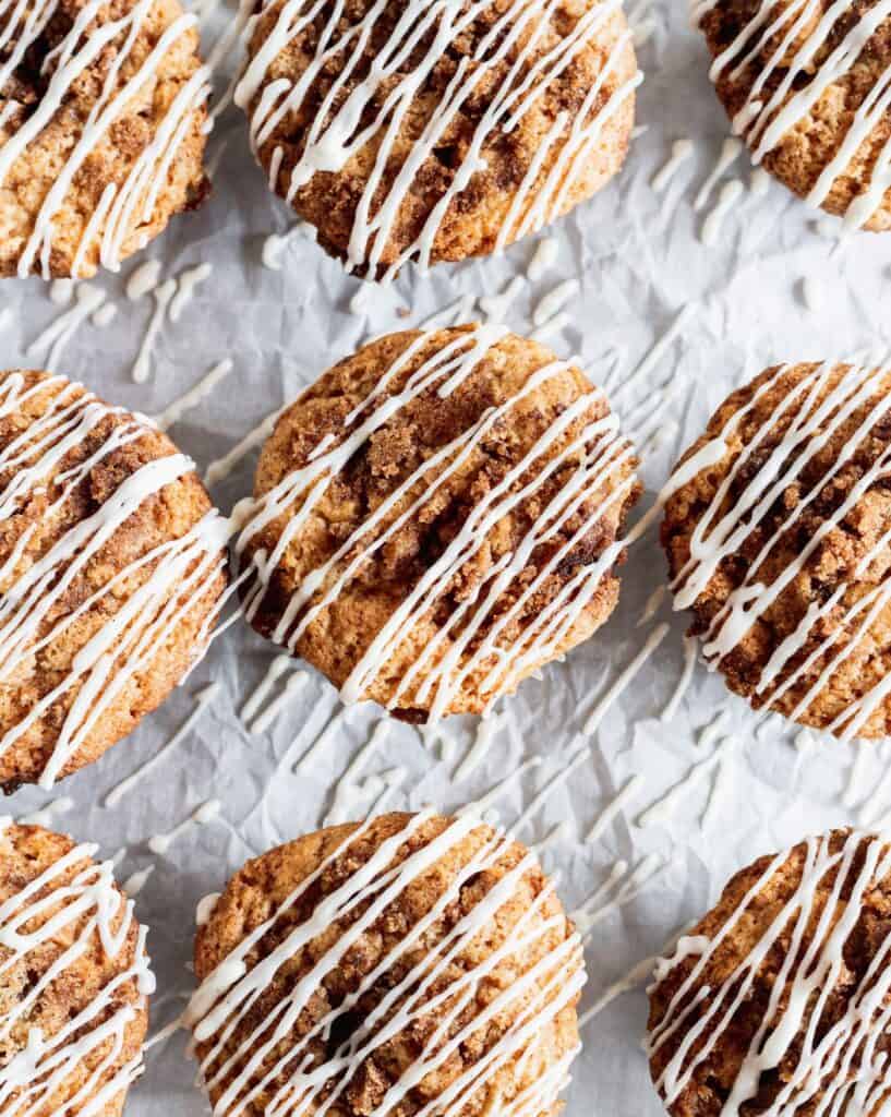 Rows of cinnamon roll muffins with cream cheese glaze drizzled on top.