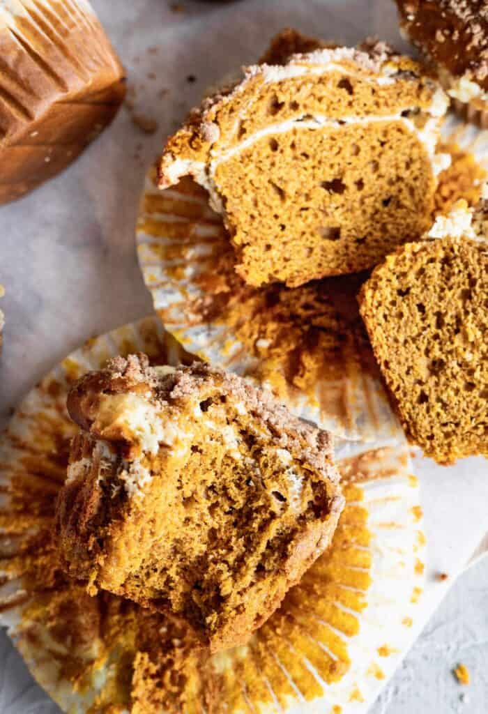 Pumpkin cheesecake muffins split in half to show off the cheesecake layer.