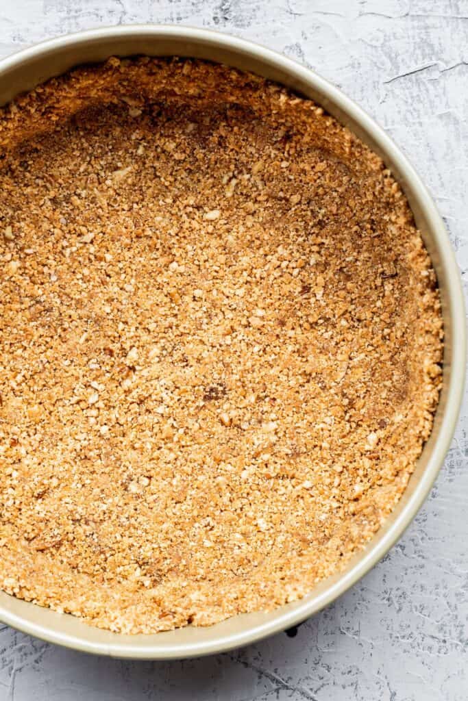 Pecan graham cracker crust compact in a spring form pan.