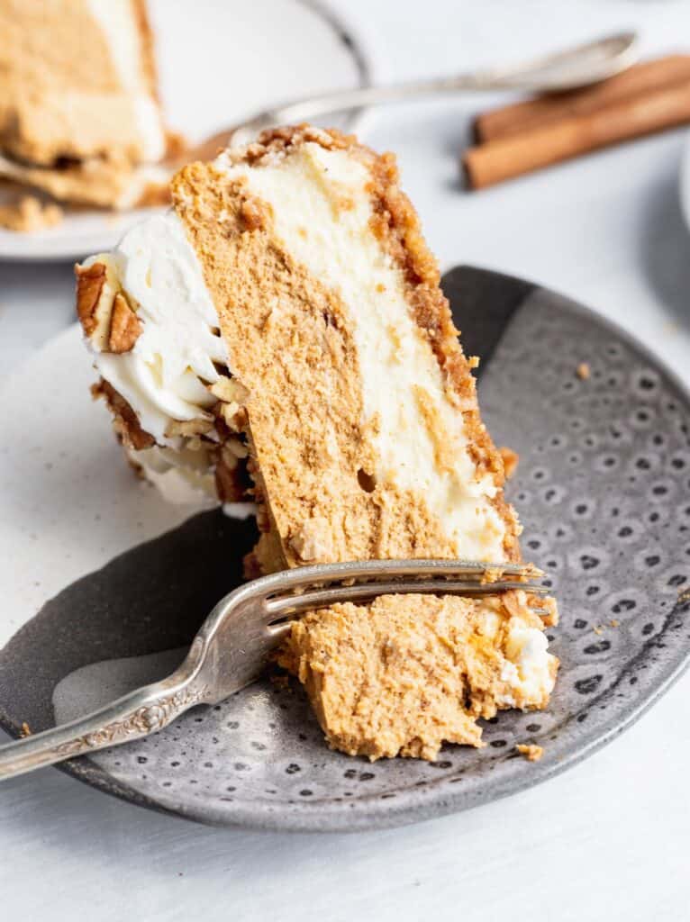 1 slice of double layer pumpkin cheesecake with a fork slicing through it.