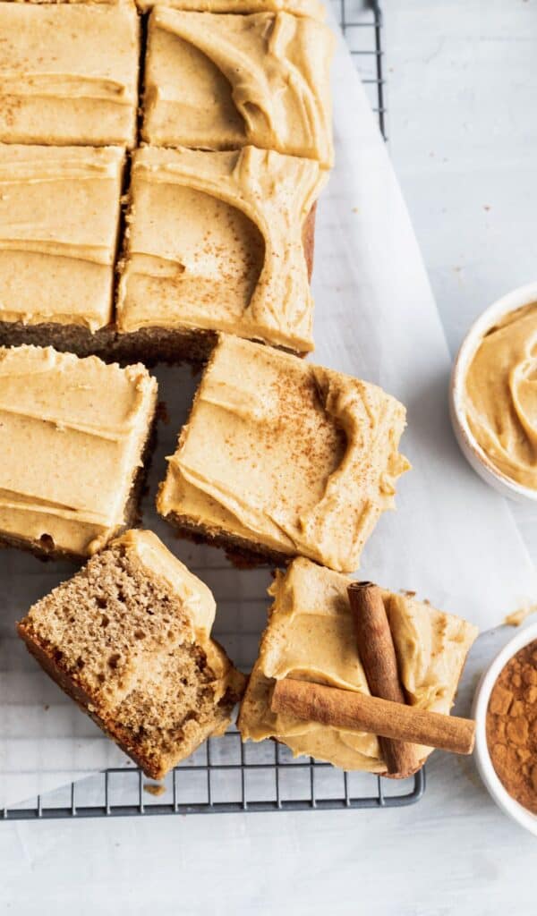 A few slices of spice sheet cake with pumpkin frosting pulled apart on a cooling rack.