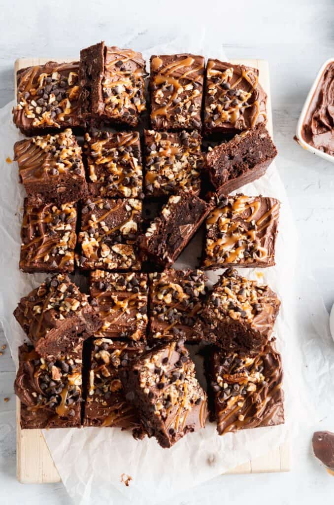 Salted caramel turtle brownies cut into squares with a few pieces on the side.
