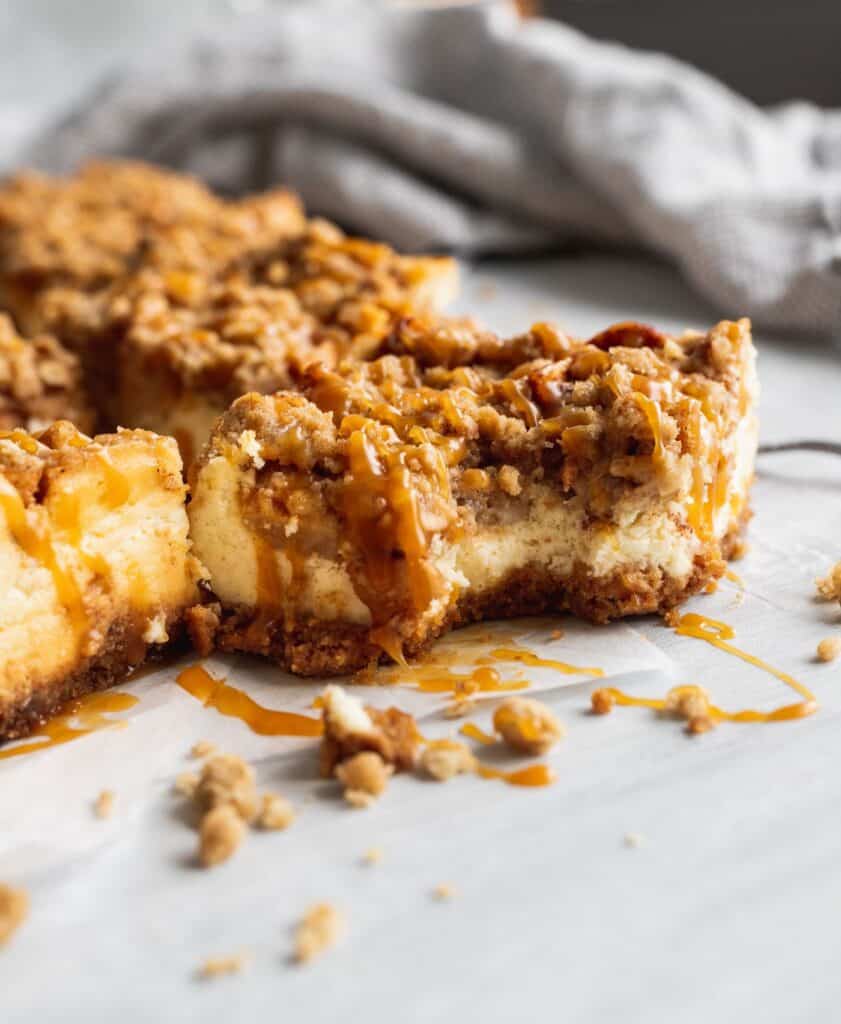 A bite taking out of a caramel apple cheesecake bars.