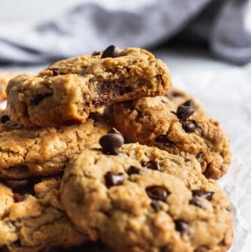 A pile of oatmeal peanut butter chocolate chip cookies with 1 cookie with a bite missing on top.