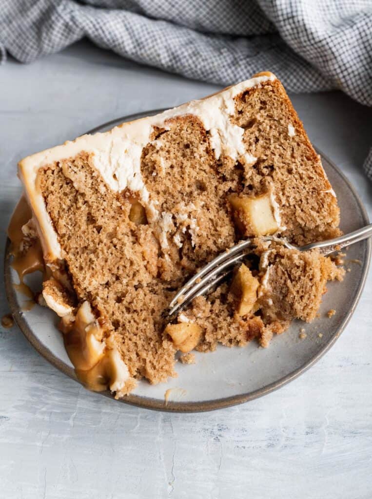 Close up of a cake slice of caramel apple spice cake with a fork inserted.