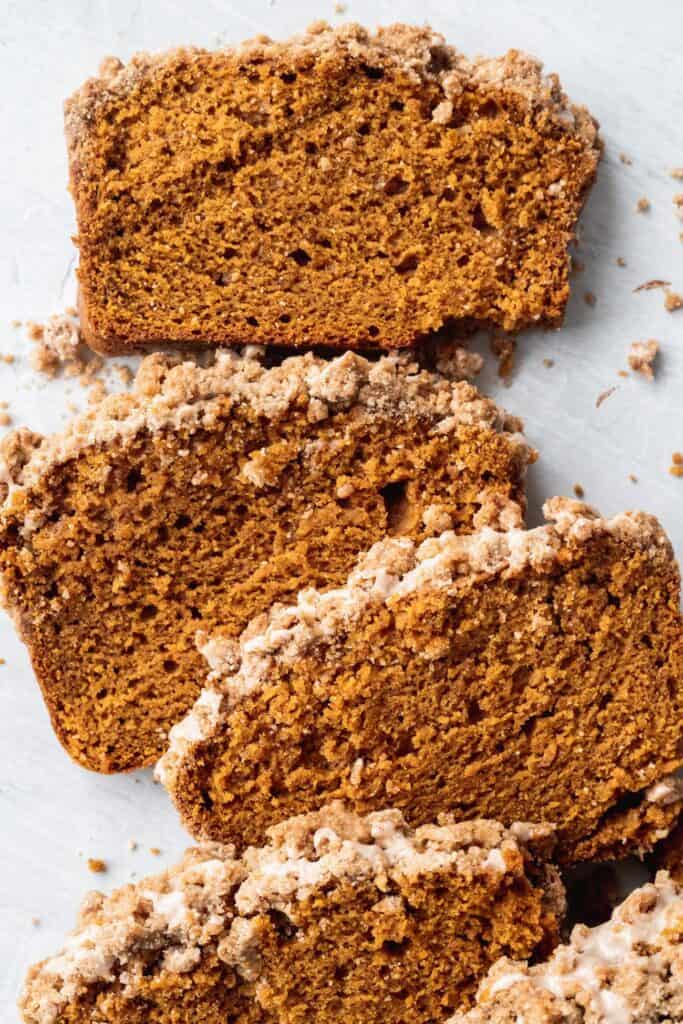 Close up of slices of pumpkin bread with cinnamon icing and pumpkin spice streusel.
