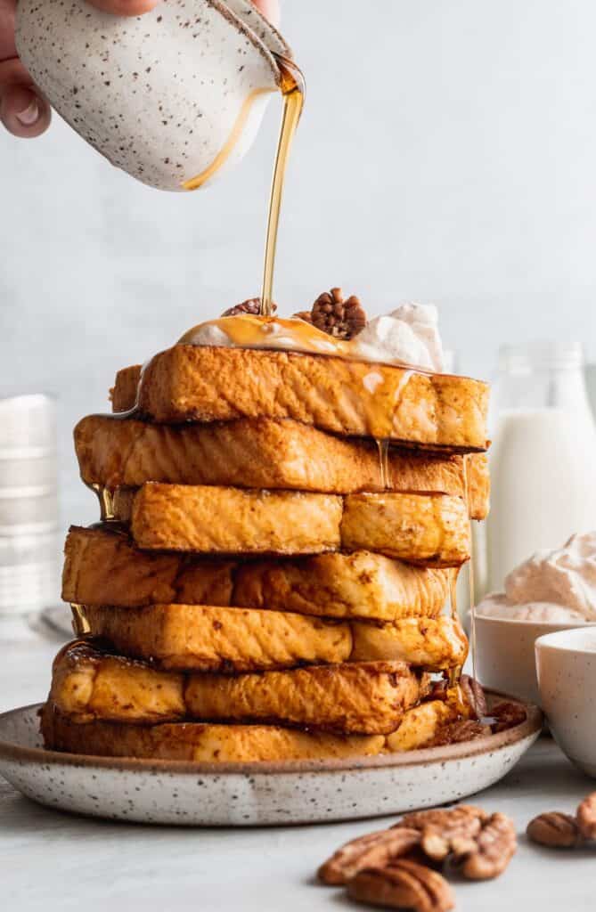 Huge stack of pumpkin spice french toast pouring syrup down.
