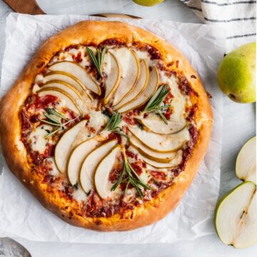 Homemade pear pancetta pizza with baked pears on top of pizza.
