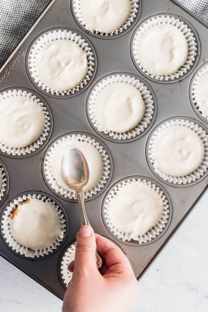Filled muffin tin with a spoon smoothing the batter