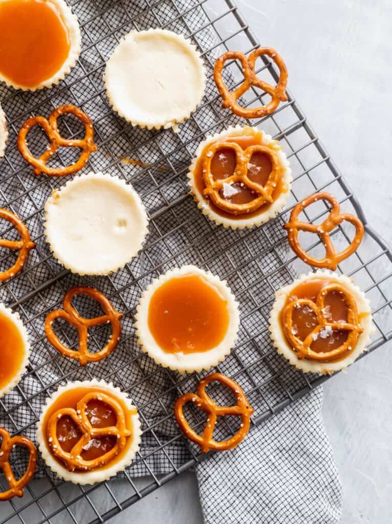 Decorating mini cheesecakes with caramel and pretzels.