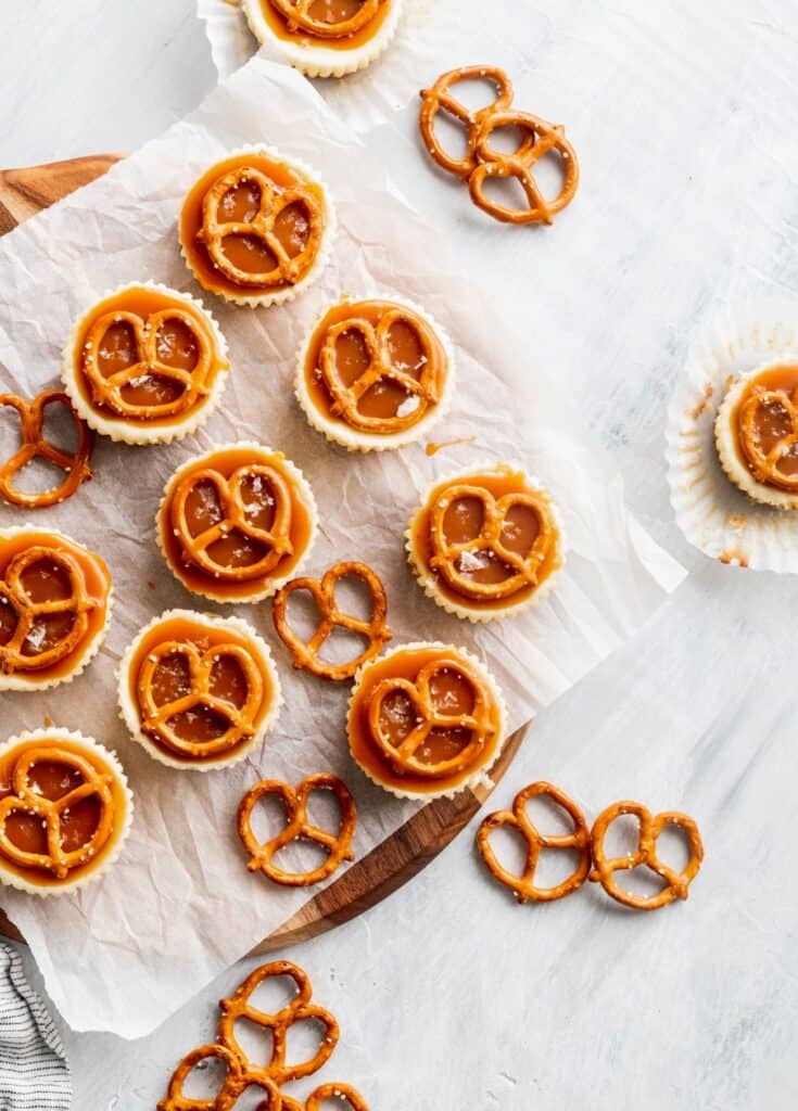 Pretzel salted caramel mini cheesecakes on a cutting board.