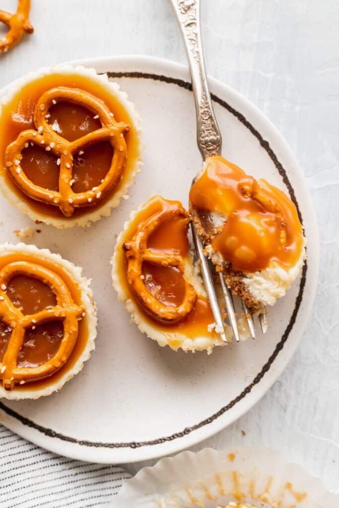 A fork inserted in a pretzel salted caramel mini cheesecake