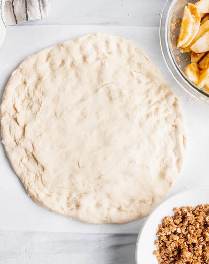 Pizza dough on a parchment paper.