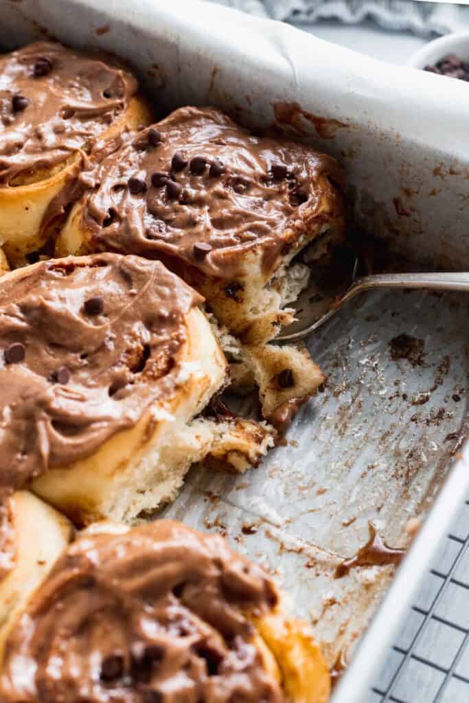 Use a pie cutter to lift a chocolate chip cinnamon roll out of pan.