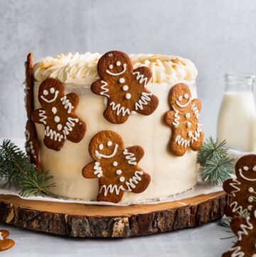 Moist gingerbread cake homemade on a wooden board with gingerbread cookies.