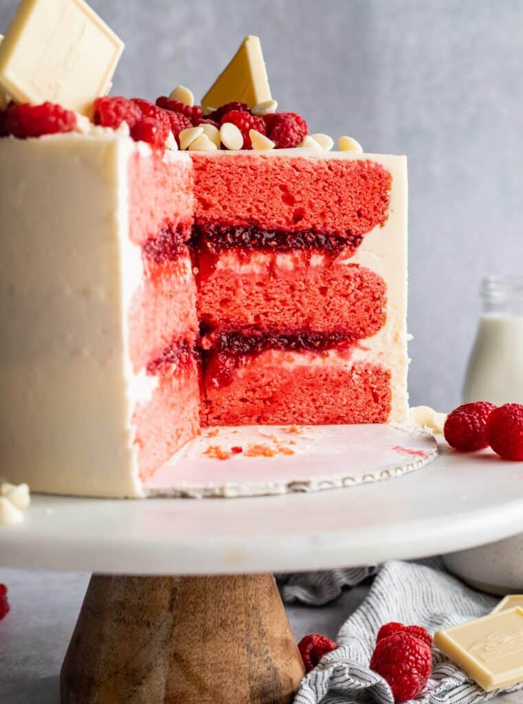 Cut into raspberry cake on a cake stand.