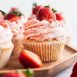 Strawberry filled cupcakes on a wood platter.