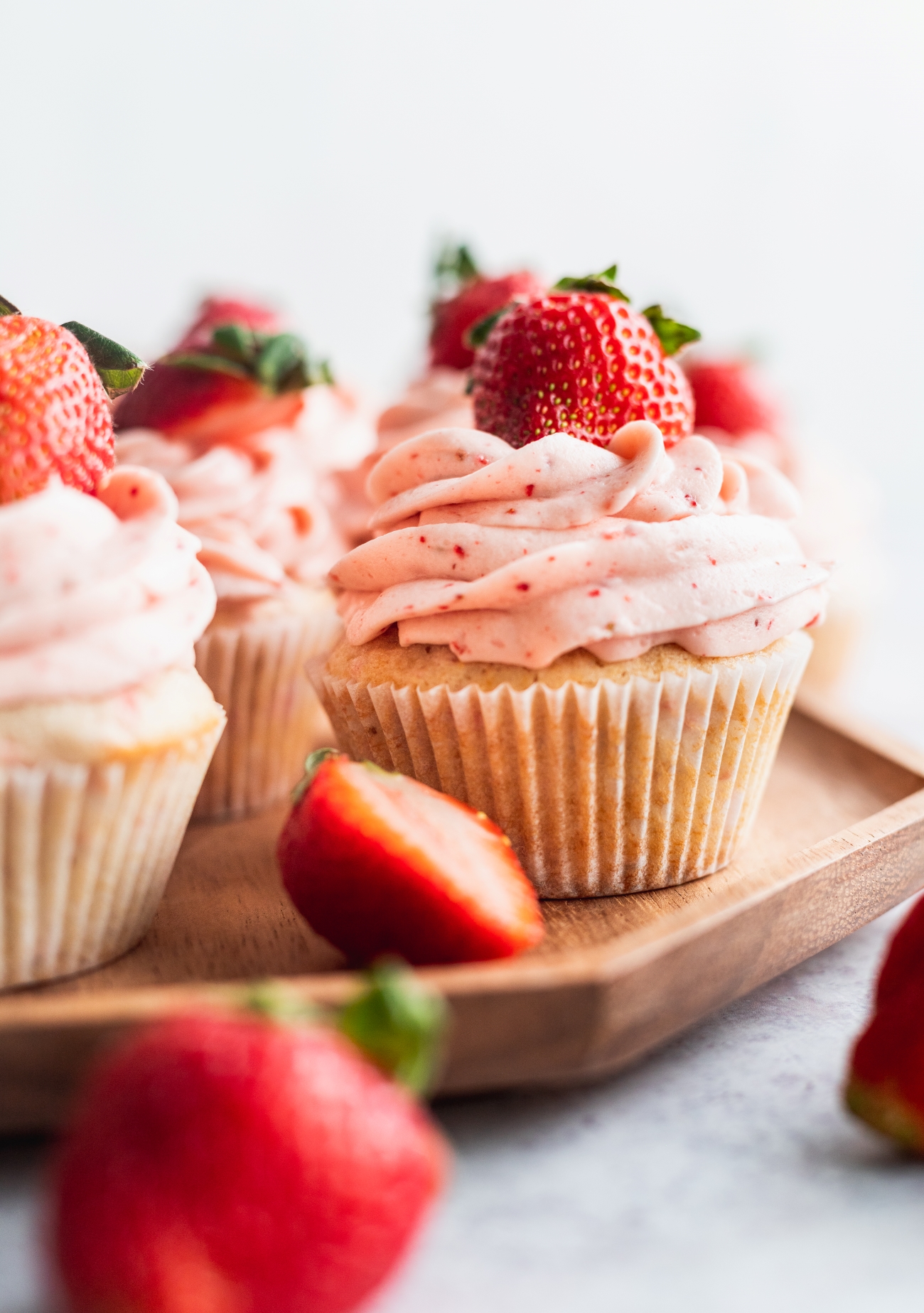 Strawberry filled cupcakes on a wooden platter.