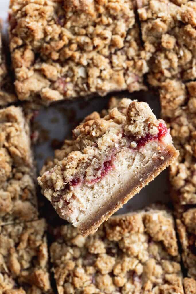 Peanut butter and jelly cheese cake bars with a bar up.