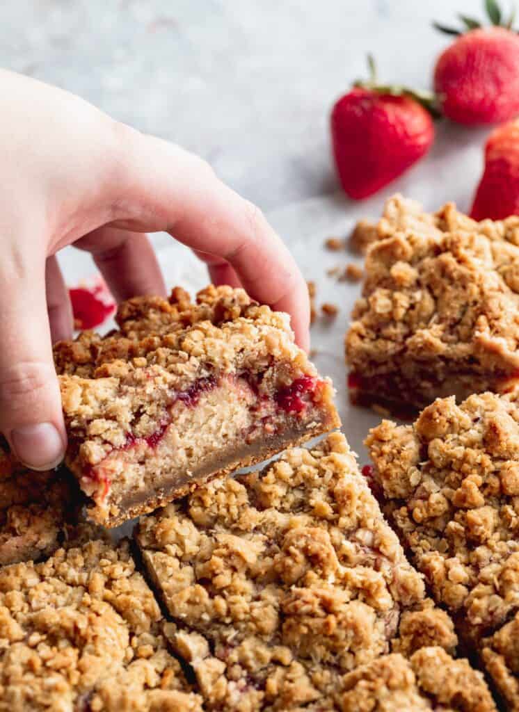 A hand lifting a cheesecake bar up.