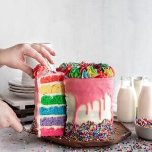 Birthday rainbow cake take a slice out.
