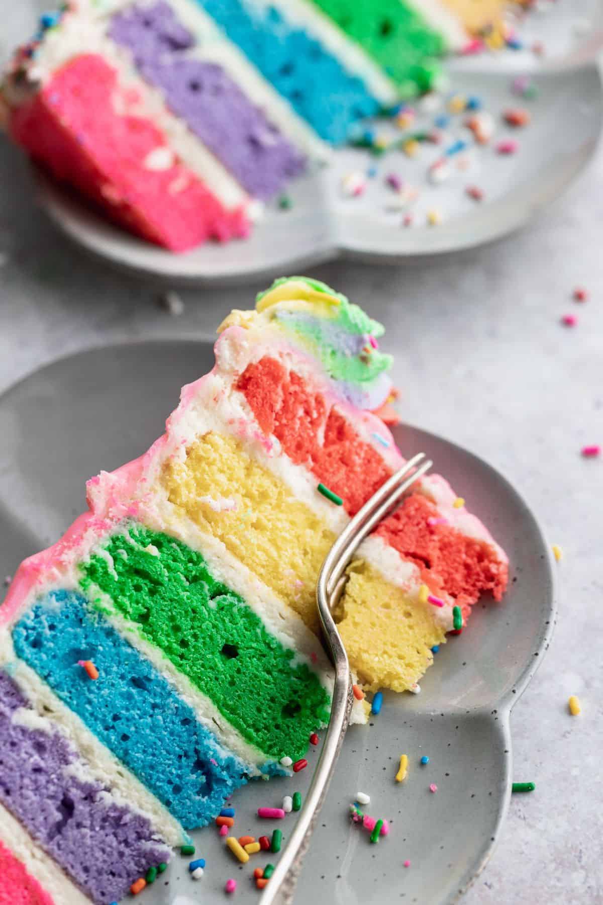Fork inserted into birthday rainbow cake.