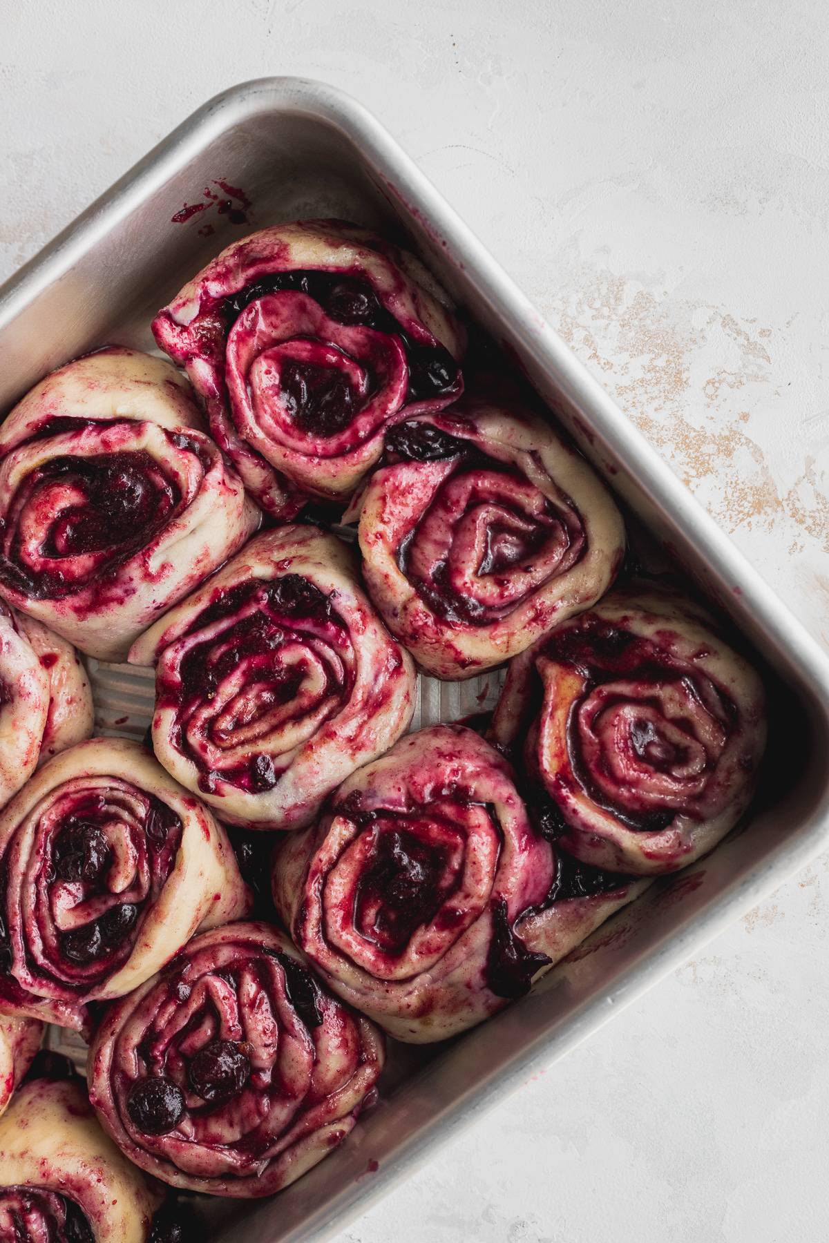 Raw cinnamon rolls rolled up in a pan.