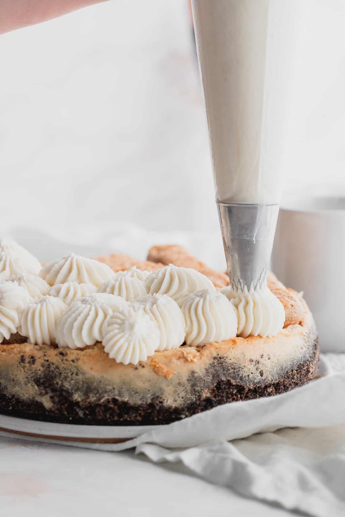 Piping whipped cream cheese on top of cheesecake.