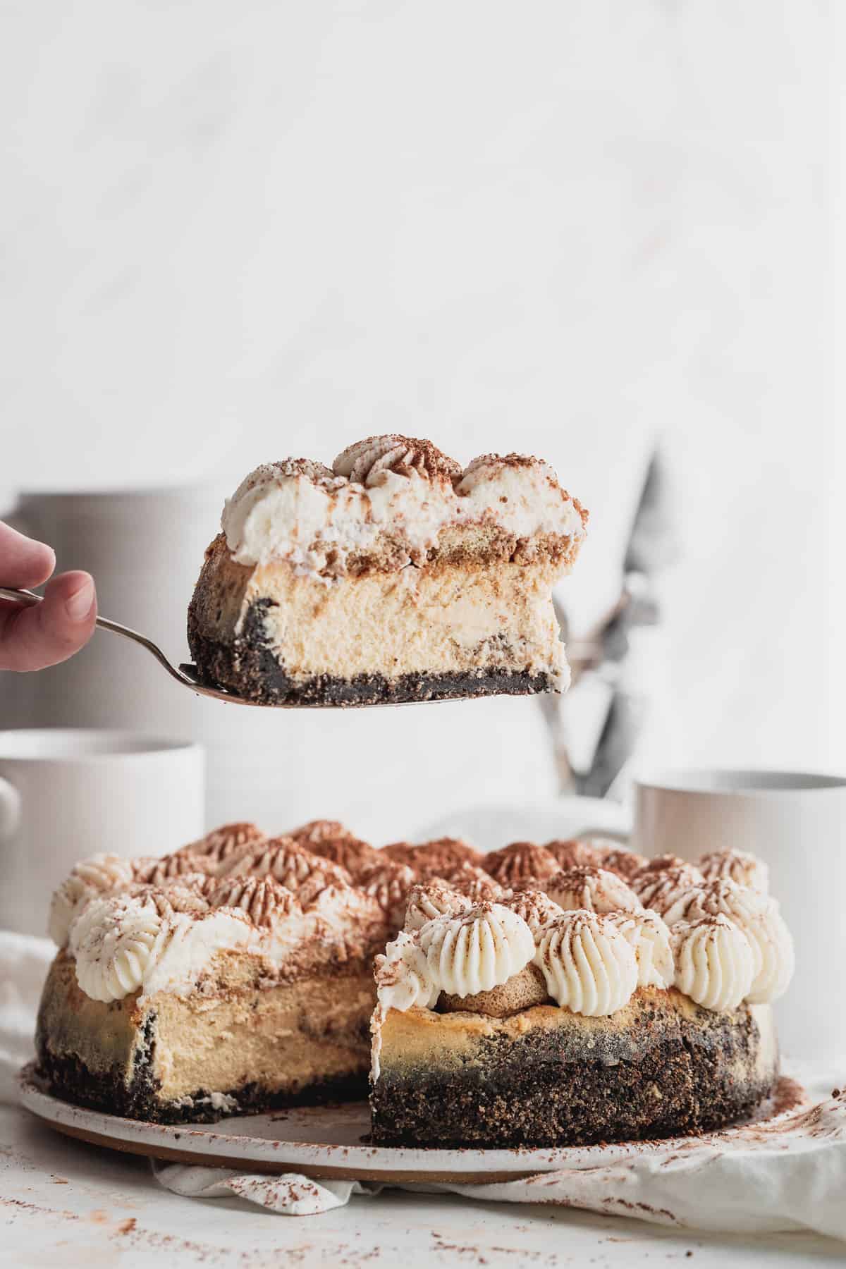 Pulling out 1 slice of tiramisu cheesecake.