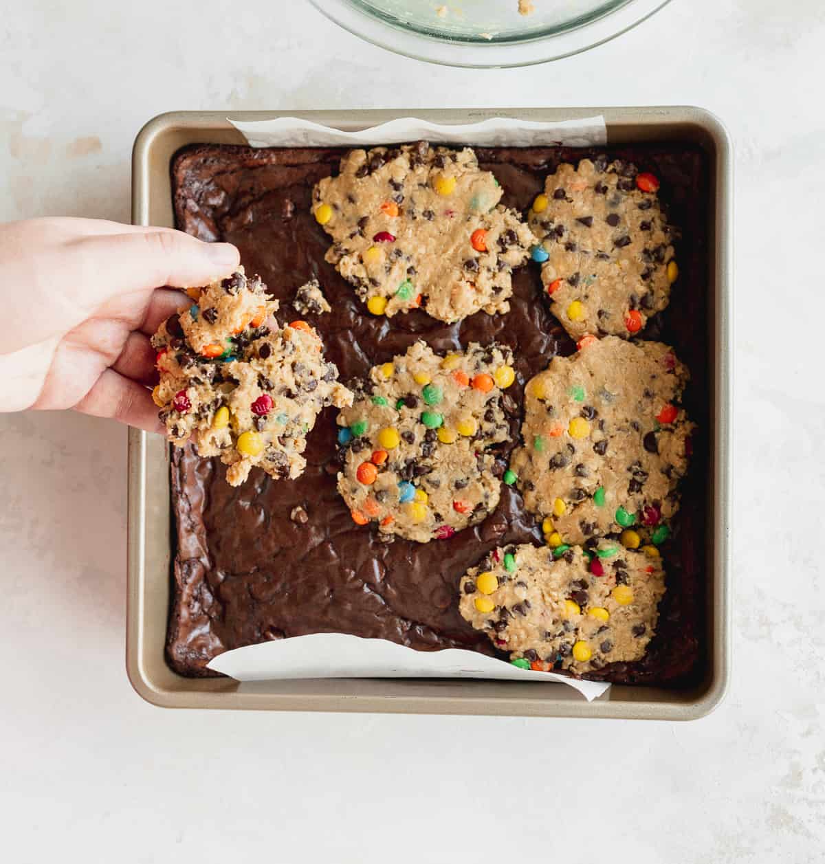 Placing cookie dough on top of brownie batter.