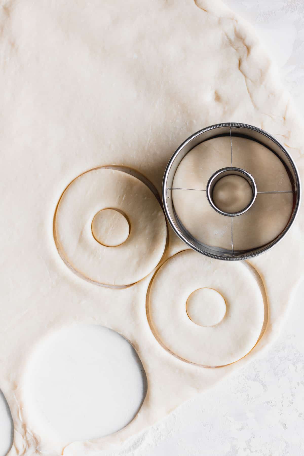 Taking a doughnut cutter to cut out doughnuts.