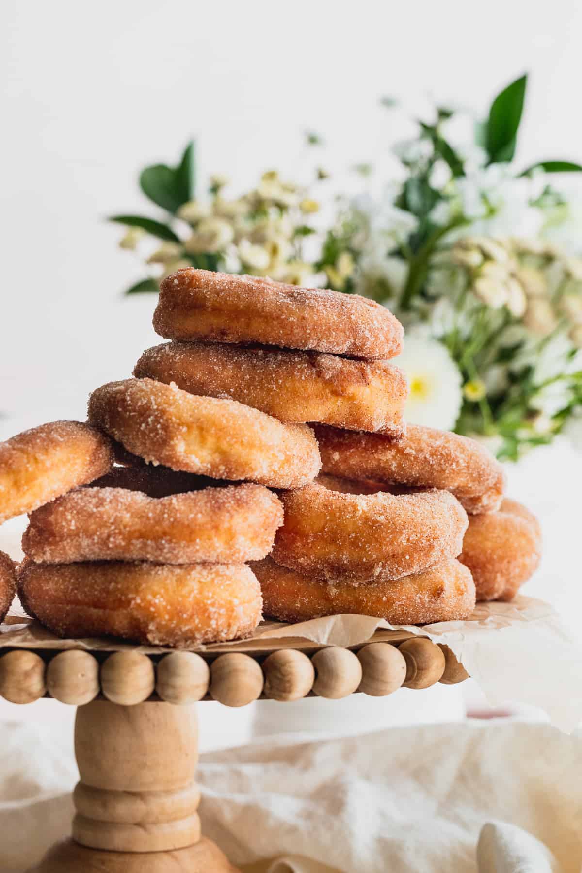 Stack of cinnamon sugar doughnuts on a cake stand.