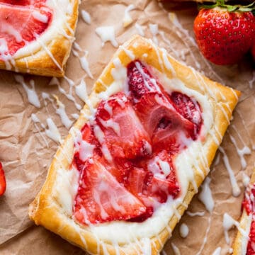 Strawberry danish on parchment paper with lemon glaze on top.