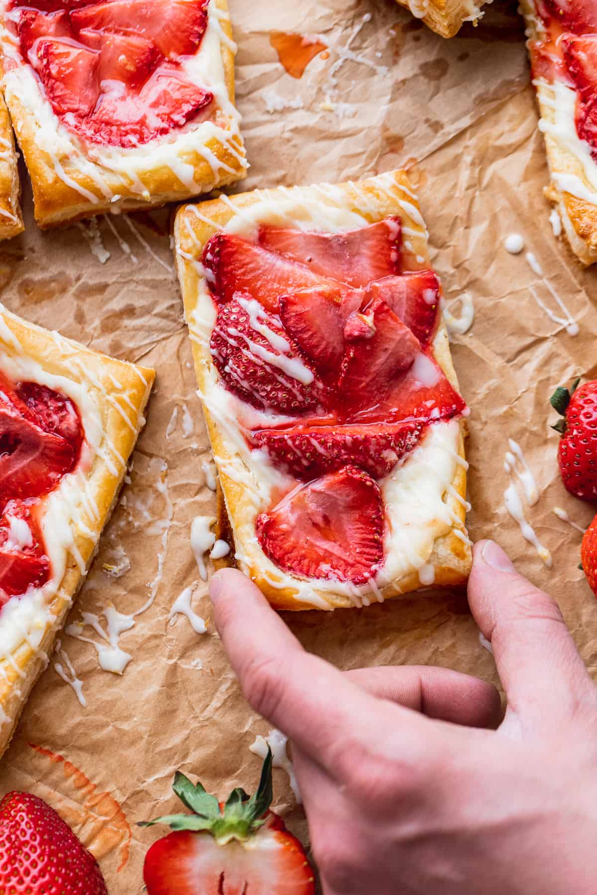 Hand coming to take strawberry danish.