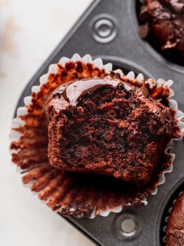 Double chocolate muffins with a bite missing in a pan.