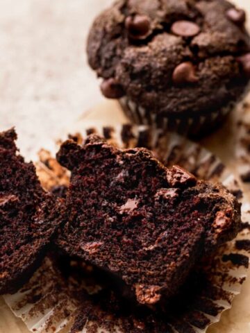 A triple chocolate muffin cut in half showing the melted chocolate chips inside.