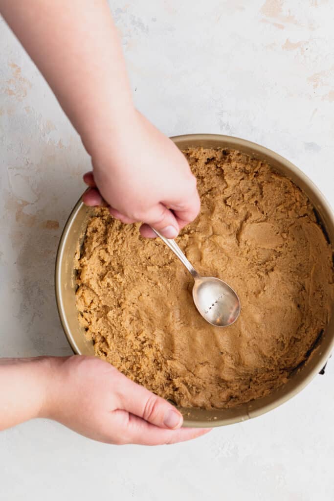 Pressing cookie dough into pan.