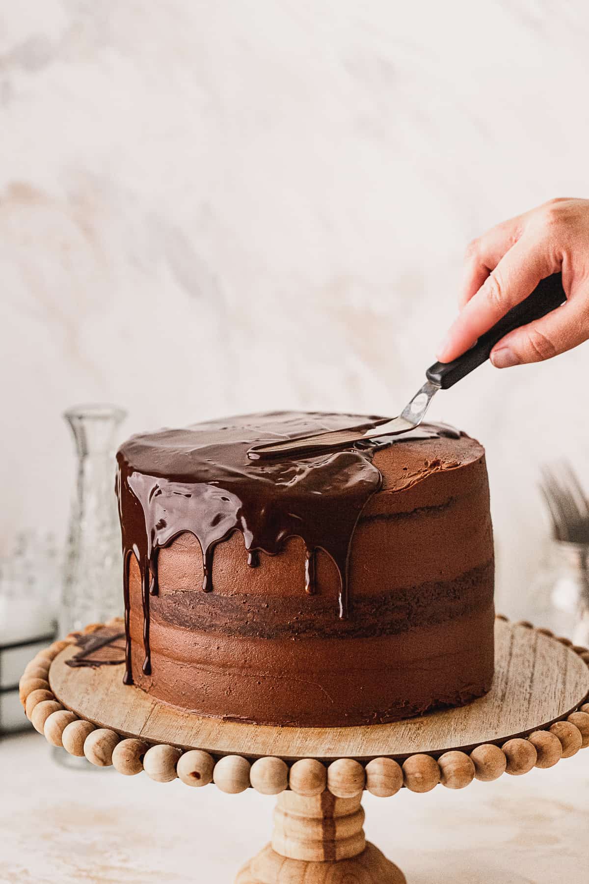 Spreading chocolate ganache on top of cake.