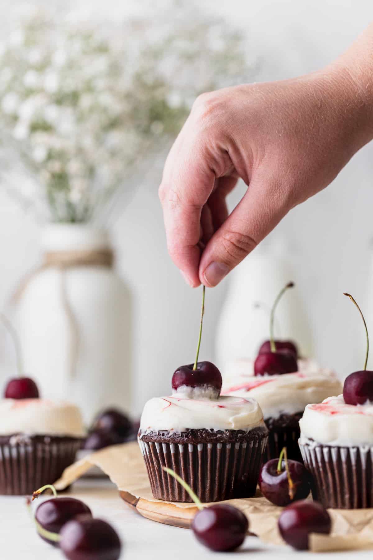 Topping the black forest cupcake with a cherry.