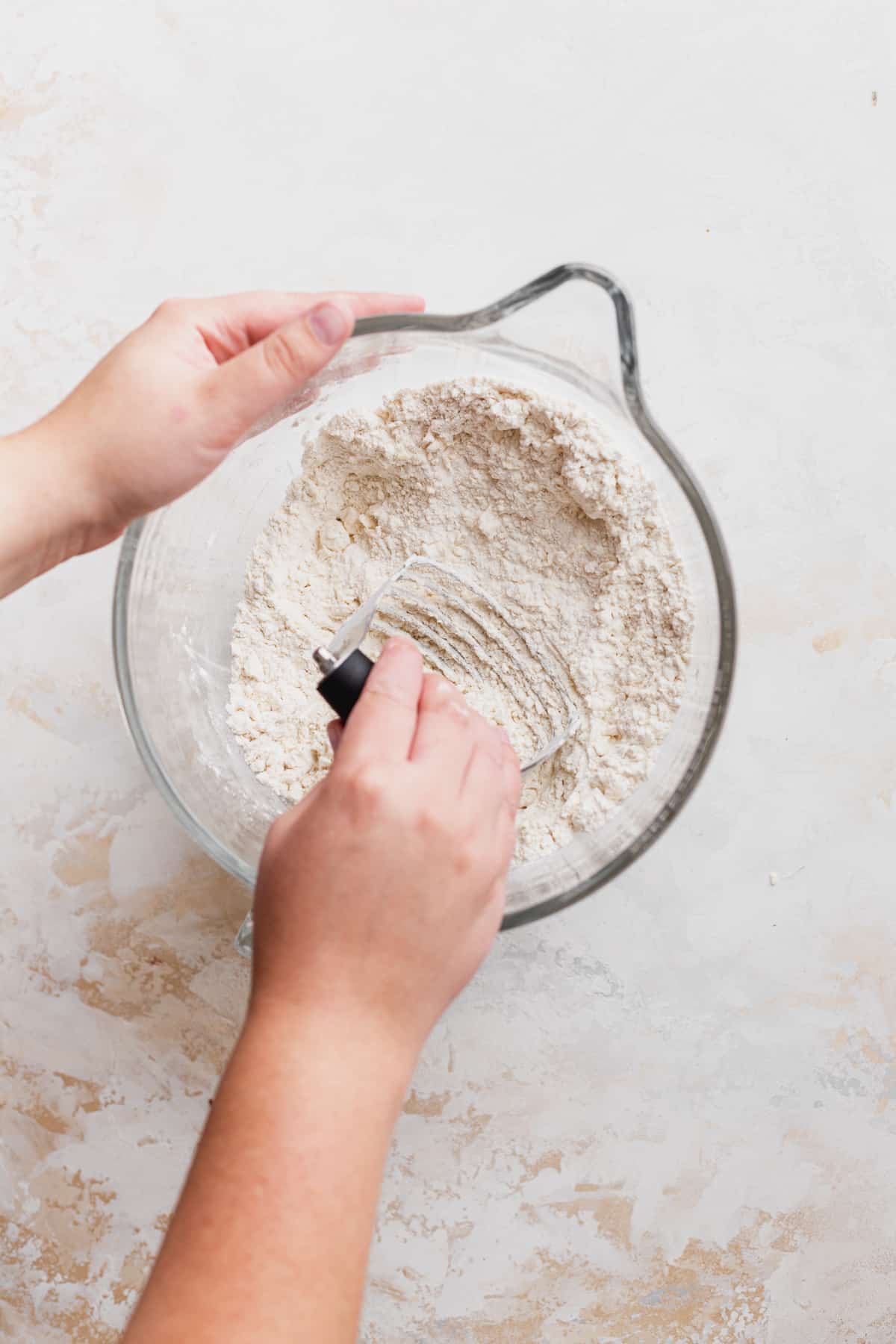 Mixing butter into flour in a glass bowl.