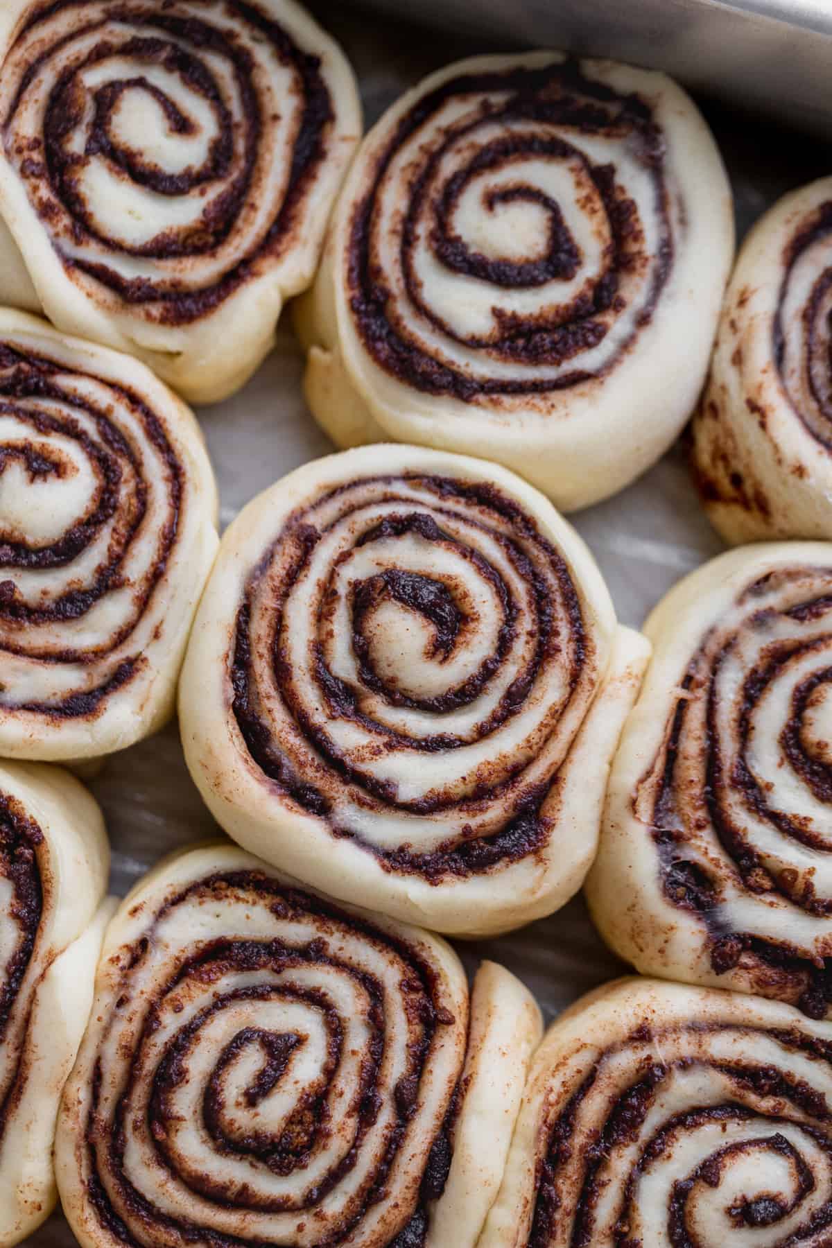 Raw cinnamon rolls in a pan.