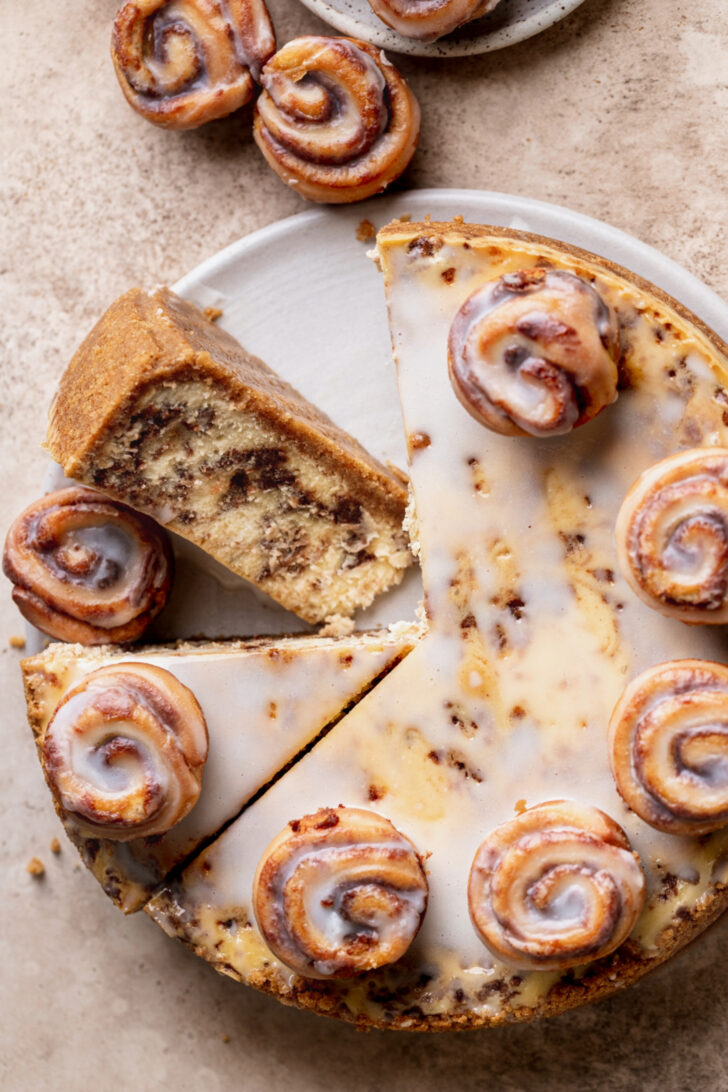 One slice of cinnamon roll cheesecake on its side with the rest of it.